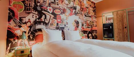 A bedroom with a large bed, a dresser, and a wall covered with various posters and images.