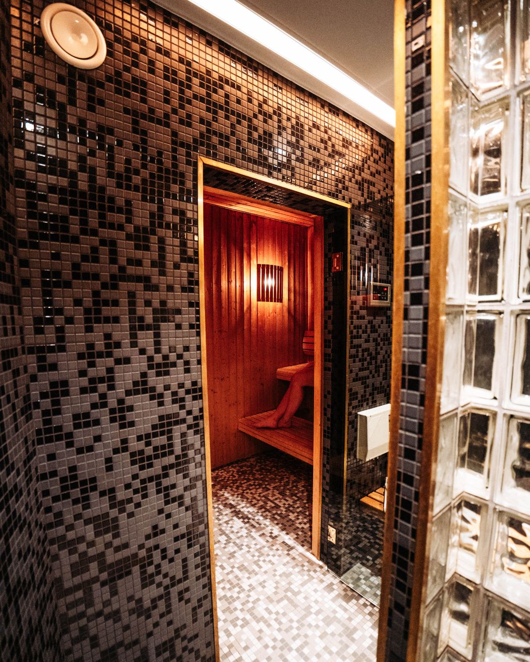 A bathroom with a tiled wall, a wooden door, and a red toilet.