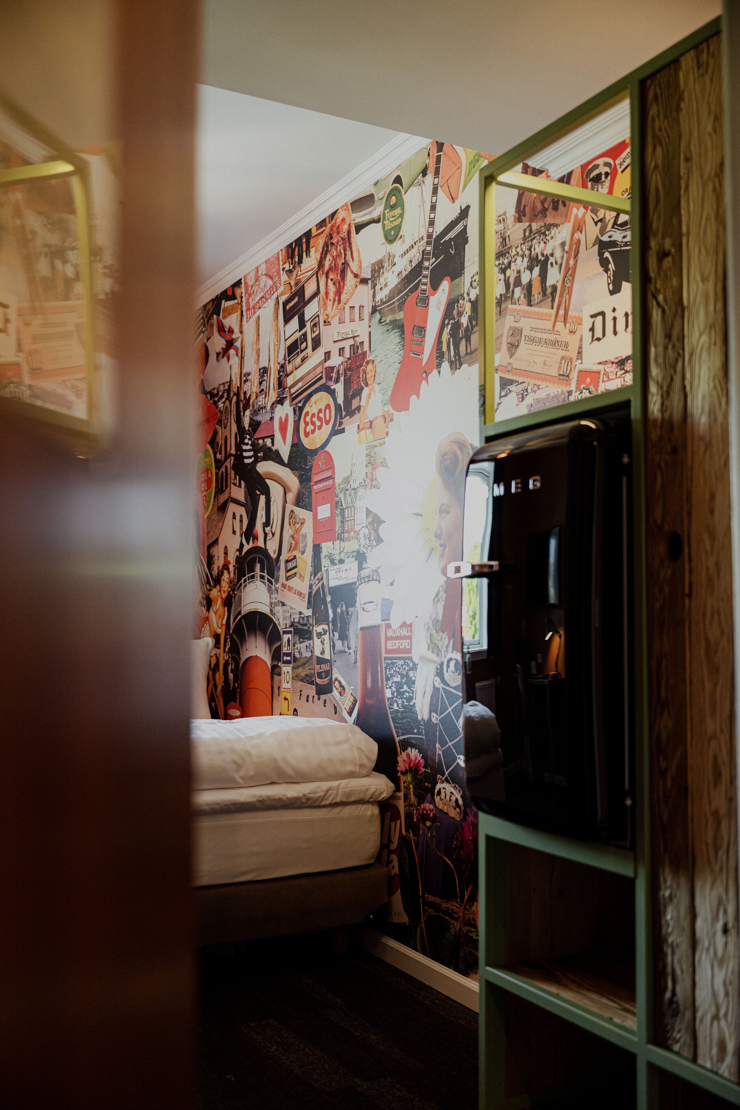Un dormitorio con una cama, un aparador y una pared decorada con carteles.