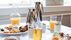 Una mesa de desayuno con diferentes platos, bebidas y acompañamientos.