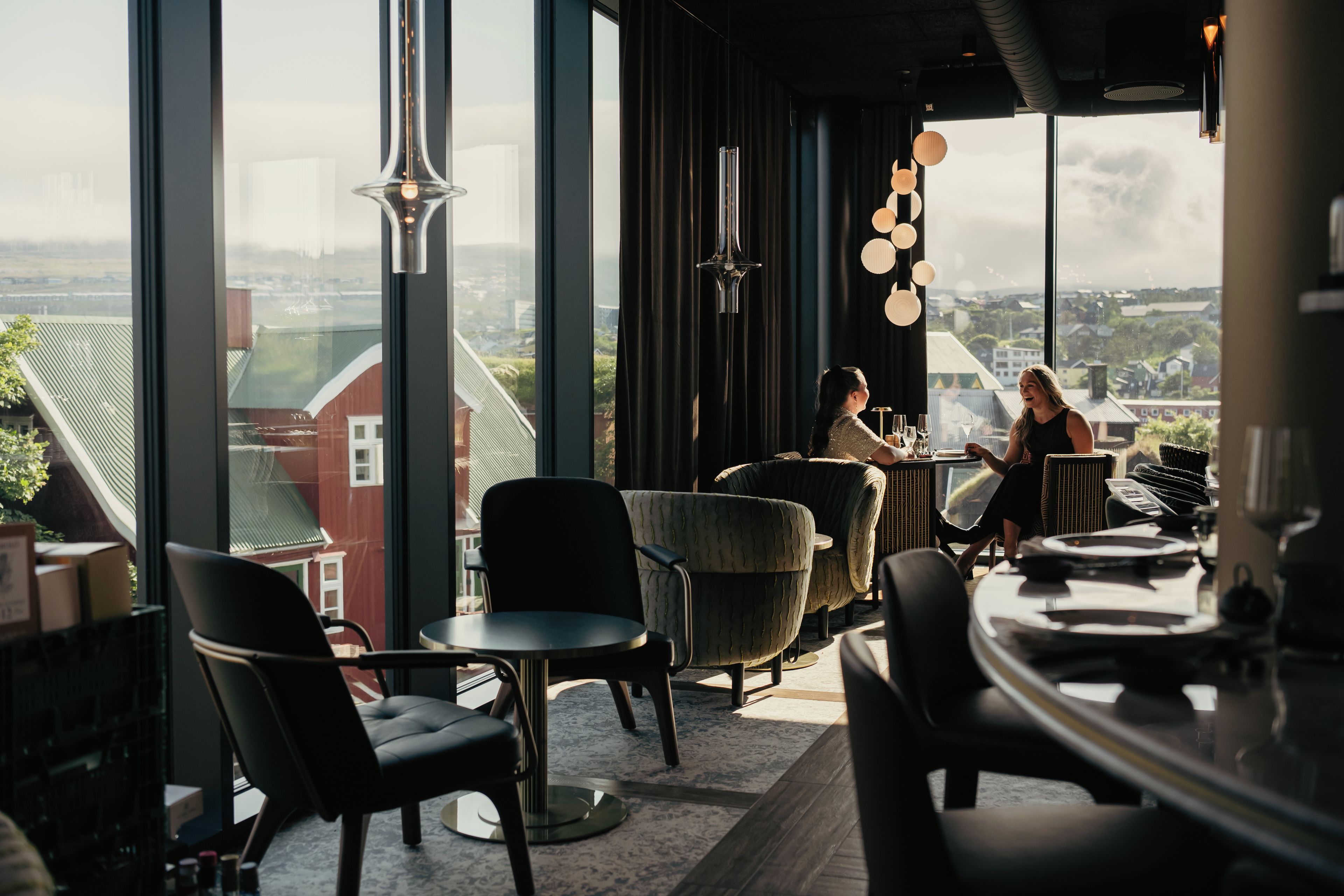 A modern interior with large windows, a bar area, and seating arrangements.