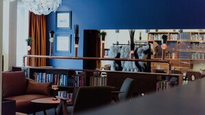 A modern library with bookshelves, a sofa, and a decorative mirror.