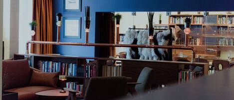 A modern library with bookshelves, a sofa, and a decorative mirror.