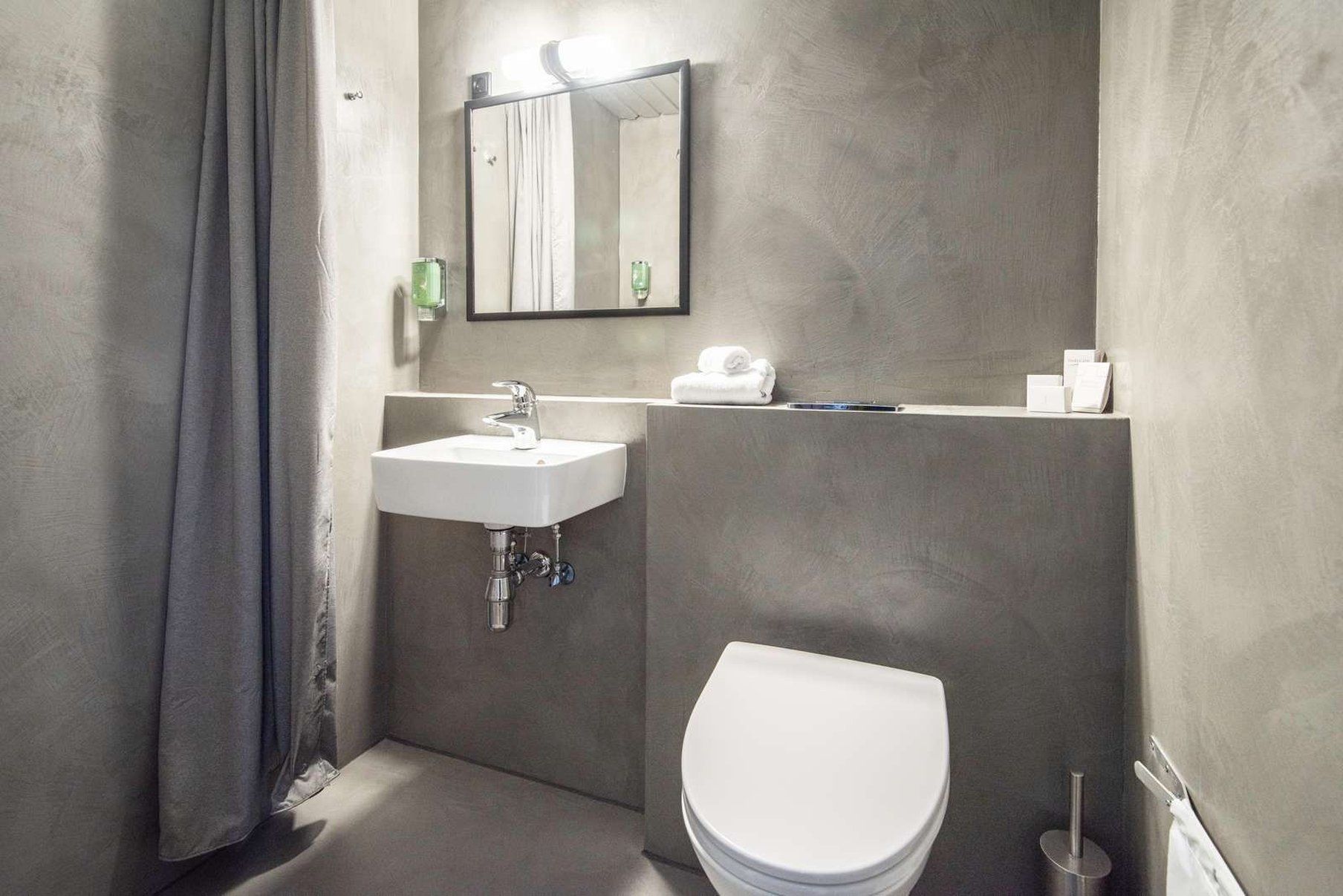 Une salle de bain moderne avec un lavabo blanc, des toilettes et un miroir au-dessus du lavabo.