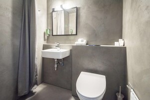 Un baño moderno con un lavamanos blanco, un inodoro y un espejo sobre el lavamanos.