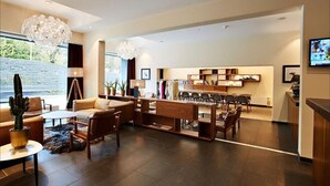 A modern living room with a sofa, coffee table, and a dining area with chairs and a wooden table.