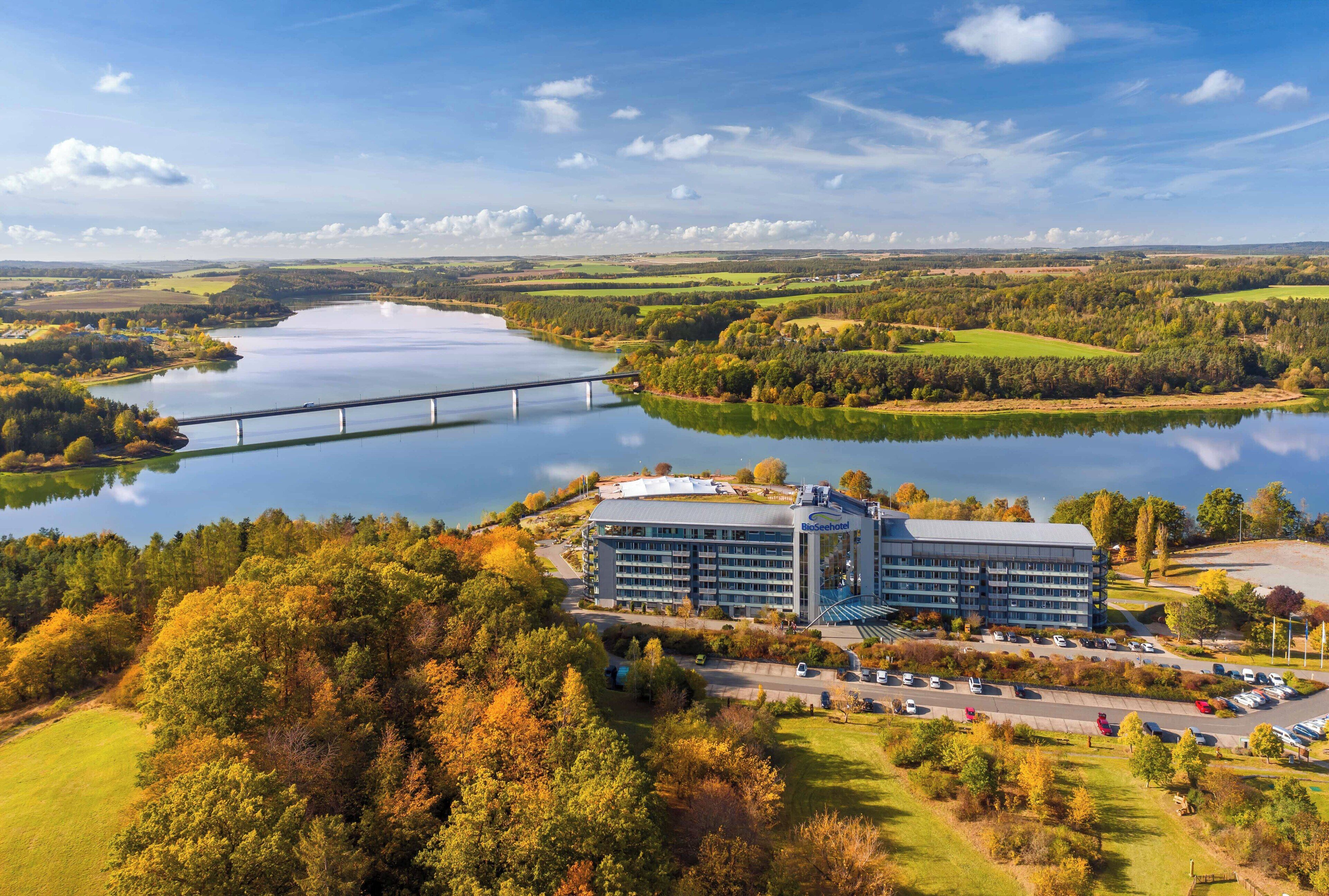 A hotel with a large building, a parking lot, and a bridge over a lake.