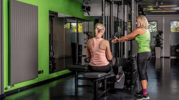 A gym with a green wall, exercise equipment, and a mirror.