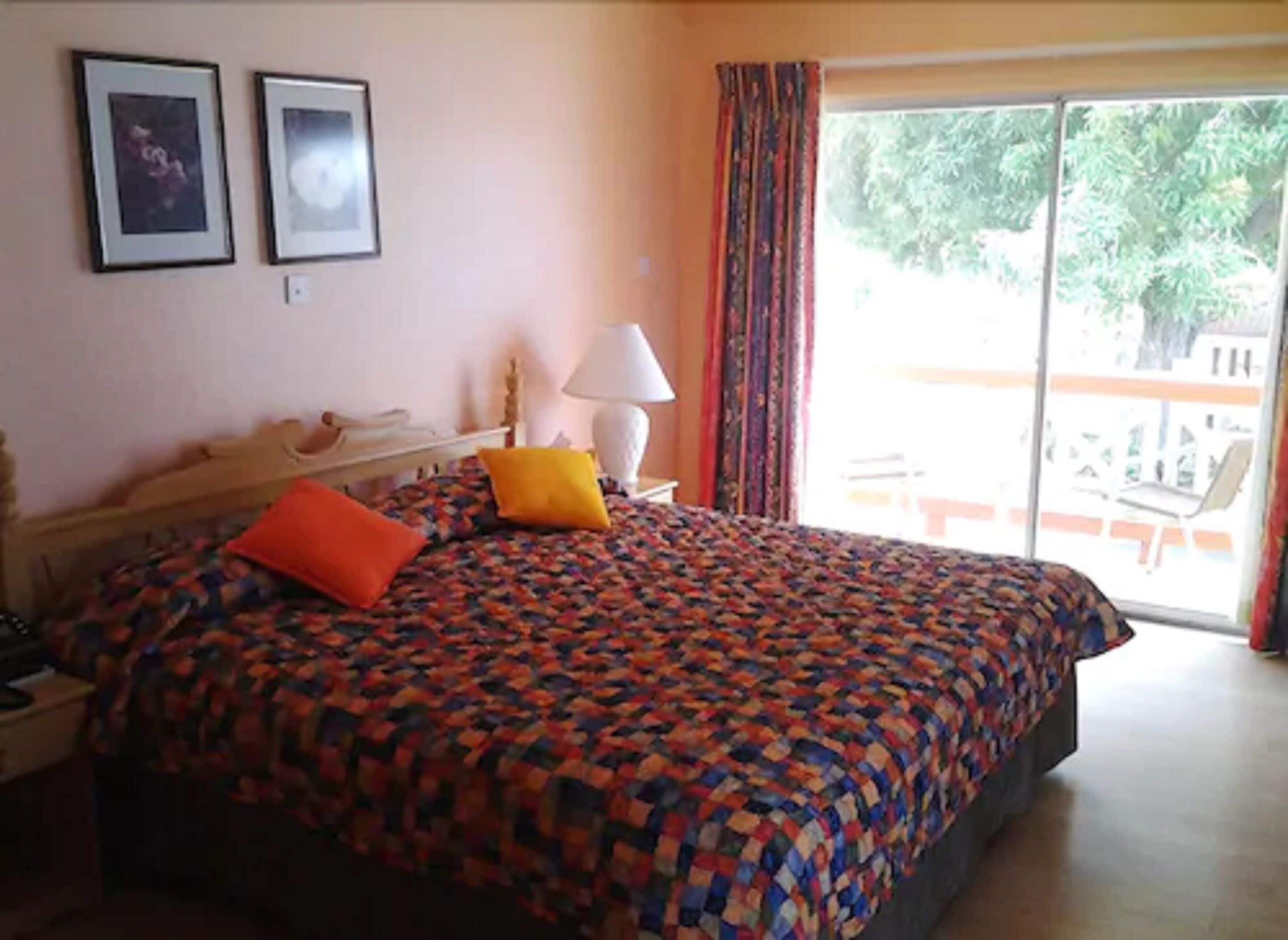 A bedroom with a bed, a nightstand, a lamp, and a window with curtains.