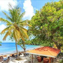 Relax in a shaded beachfront seating area with comfortable chairs and tables.