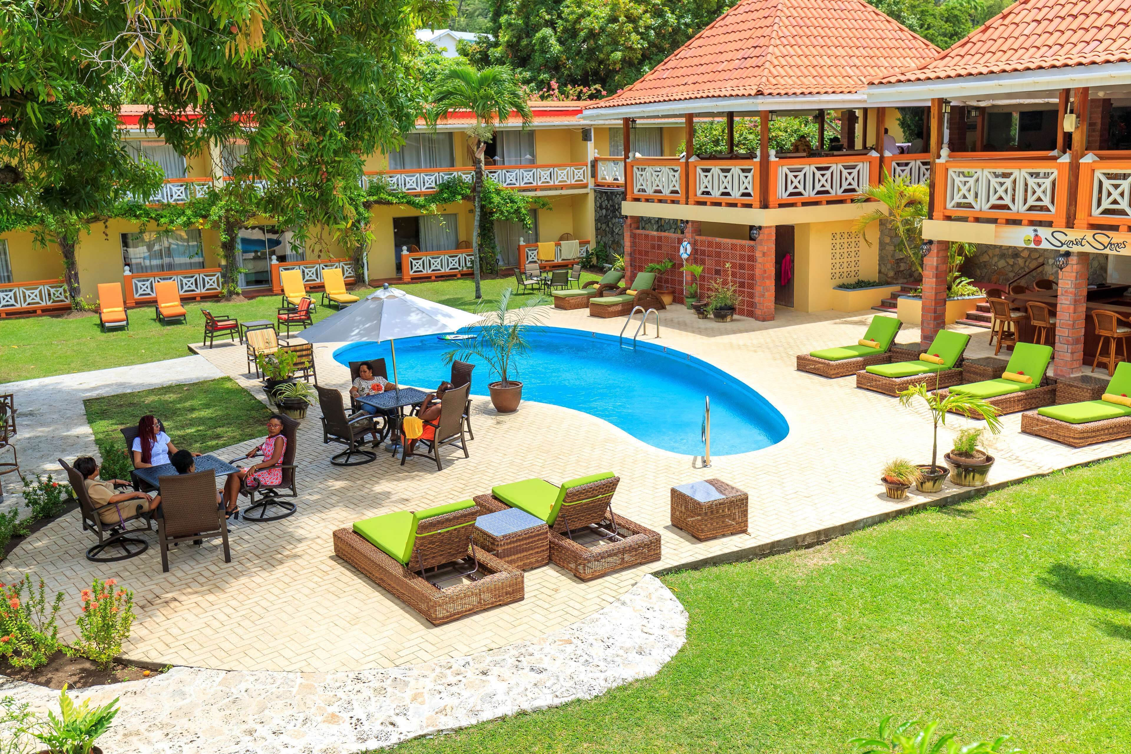 A resort with a swimming pool, outdoor seating, and a covered area with a view of the pool.