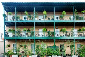 Un edificio de varios pisos con balcones, cada uno decorado con macetas y mobiliario exterior.