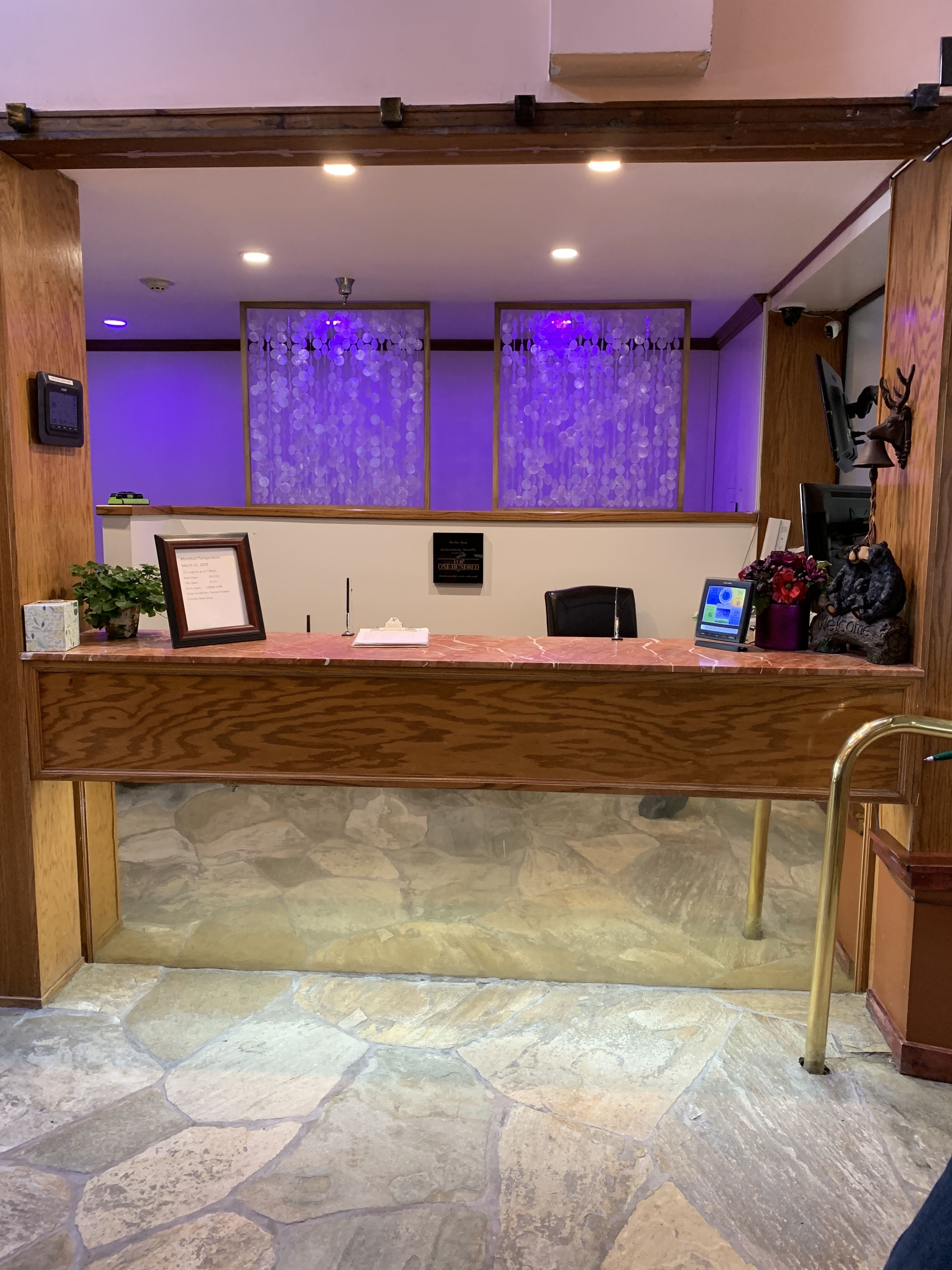 A reception desk with a stone floor, wooden paneling, and purple curtains.