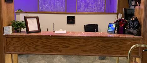 A reception desk with a stone floor, wooden paneling, and purple curtains.