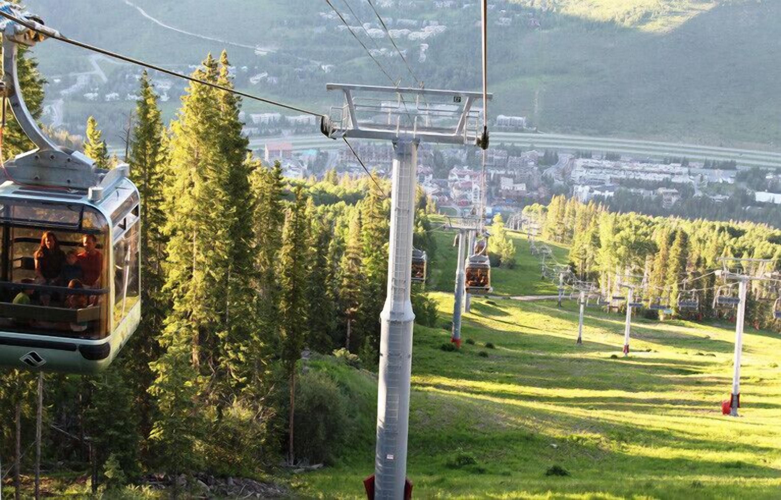 Un téléphérique dans une région montagneuse, avec une ville en arrière-plan.