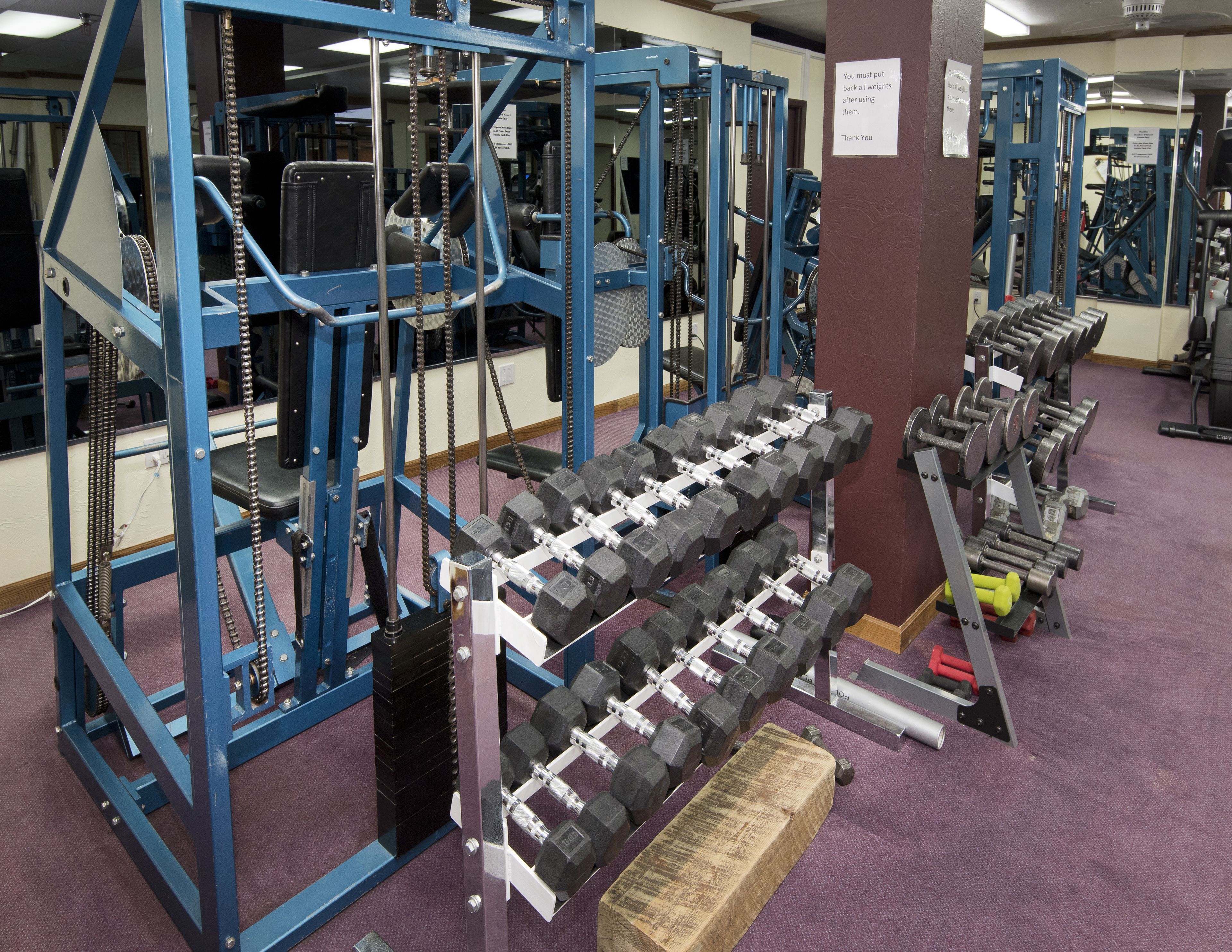A gym with weightlifting equipment, including dumbbells and weight plates.