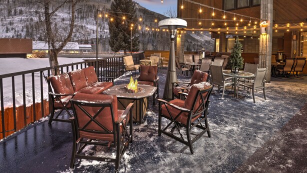An outdoor patio with leather chairs, a fire pit, and string lights. - Vail Run Resort (Vail)