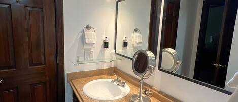 A bathroom with two sinks, a large mirror, and a wooden door.