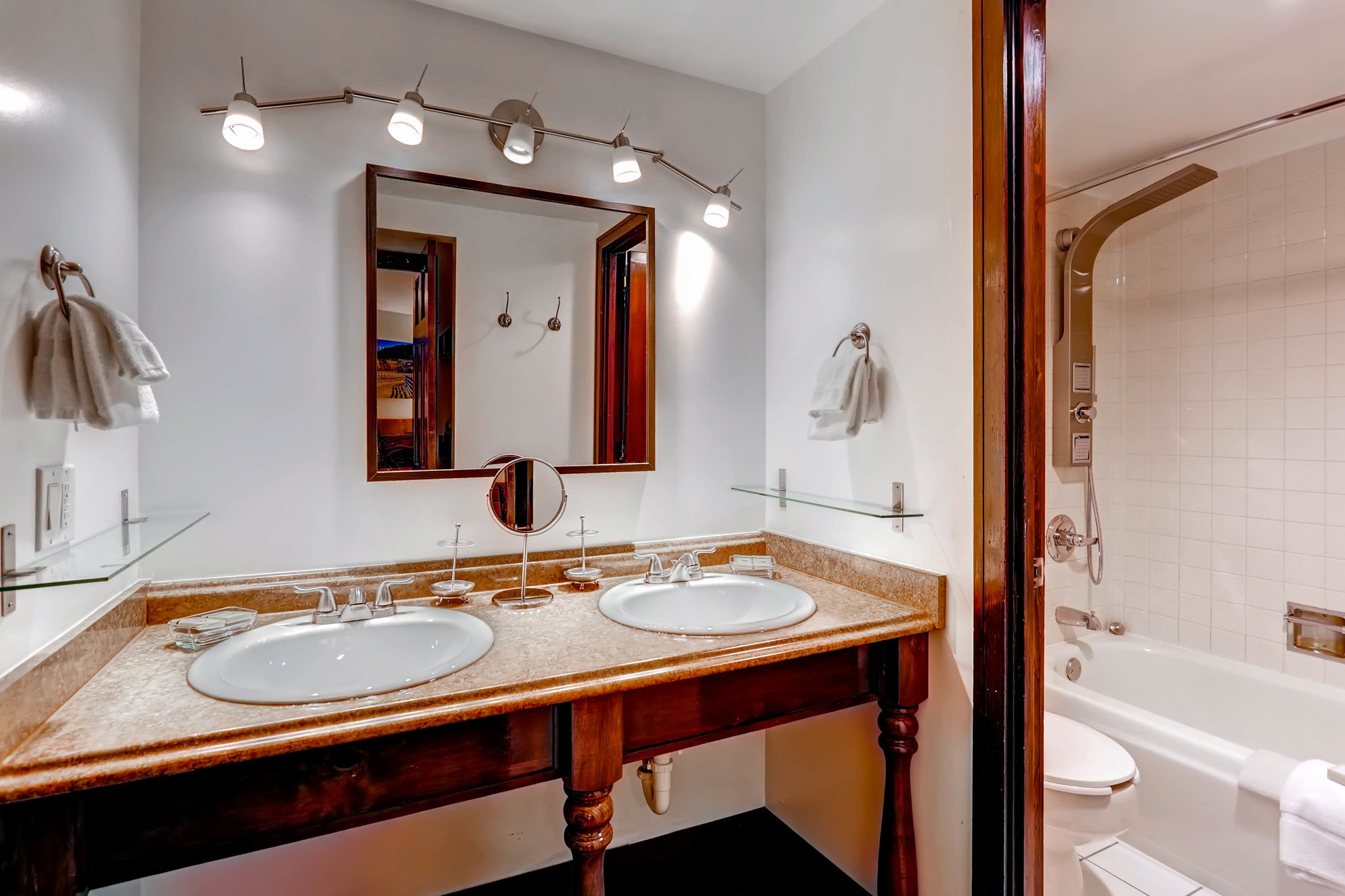 A bathroom with two sinks, a large mirror, and a shower.