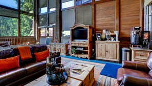 A spacious living room with a large window, a leather sofa, a coffee table, and a television. - Vail Run Resort (Vail)