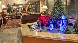 A lobby with a stone floor, a reception desk, a Christmas tree, and a fountain. - Vail Run Resort (Vail)