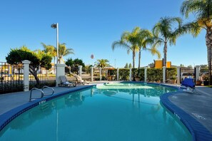 Una piscina al aire libre, sombrillas, sillones reclinables de piscina