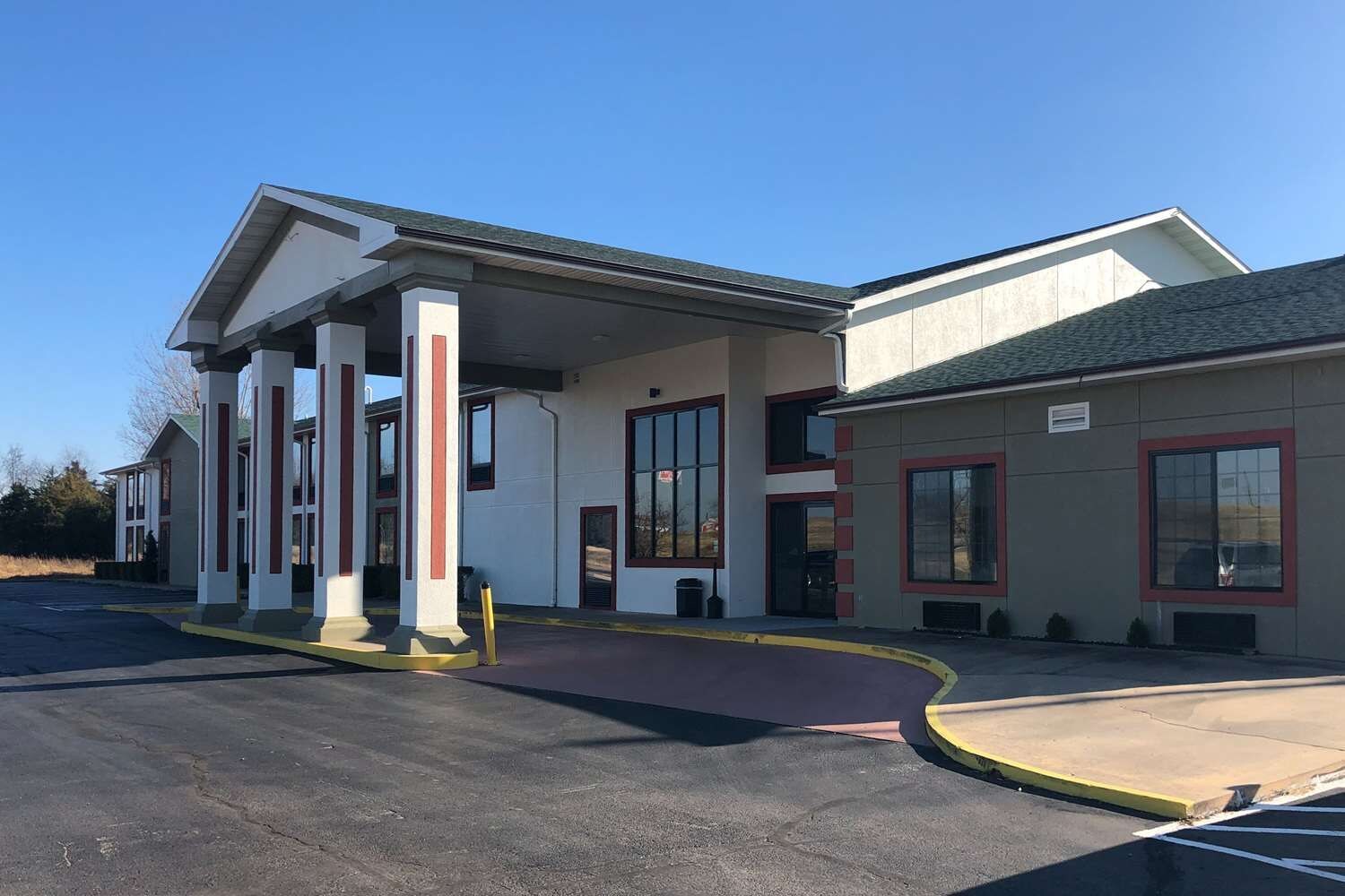 A building with a covered entrance, large windows, and a parking lot.