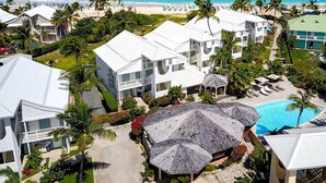 Un resort con varias edificaciones blancas, una piscina y vista al mar.