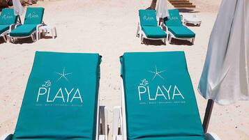 Dos filas de sillas de playa con cojines verdes y estructura blanca, con la etiqueta "La Playa" en los respaldos.