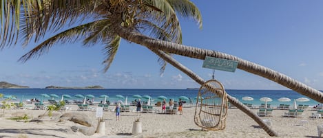 På stranden, hvidt sand, liggestole, parasoller