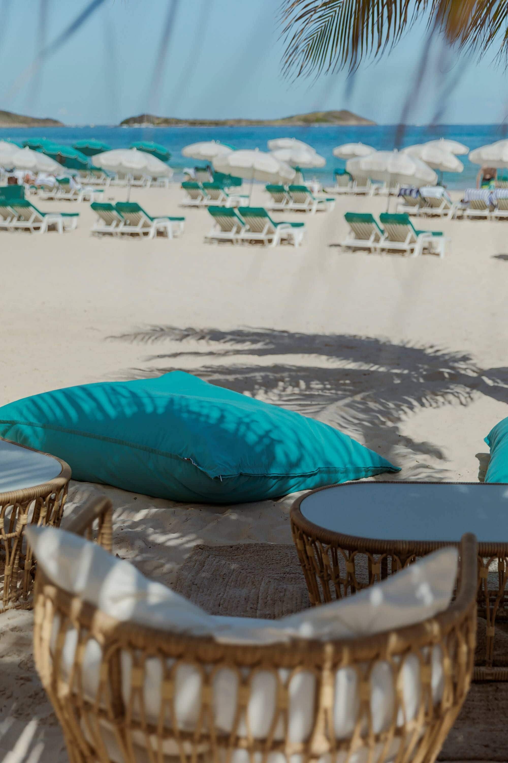 Eine Strandlounge mit Korbmöbeln und weißen Kissen mit Blick auf den Ozean.