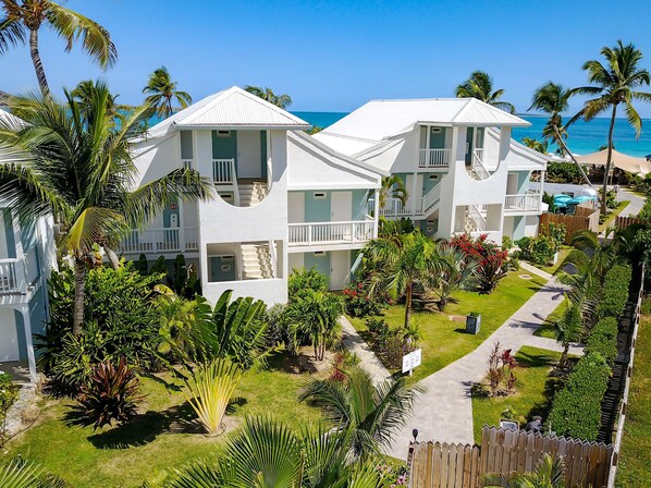 Un resort con varias edificaciones blancas, balcones y abundante vegetación.