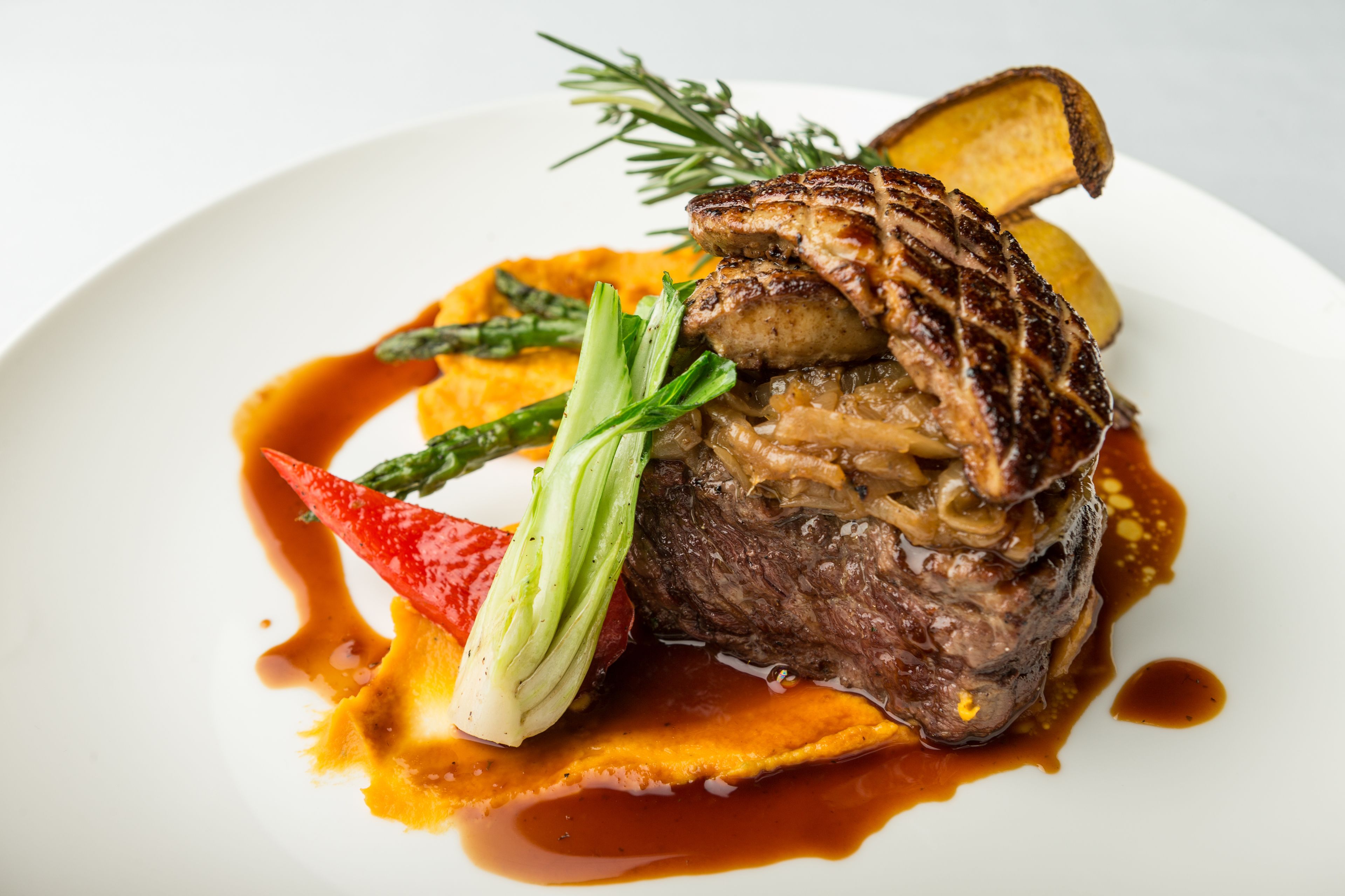 Un plato de comida con carne, vegetales y salsa.