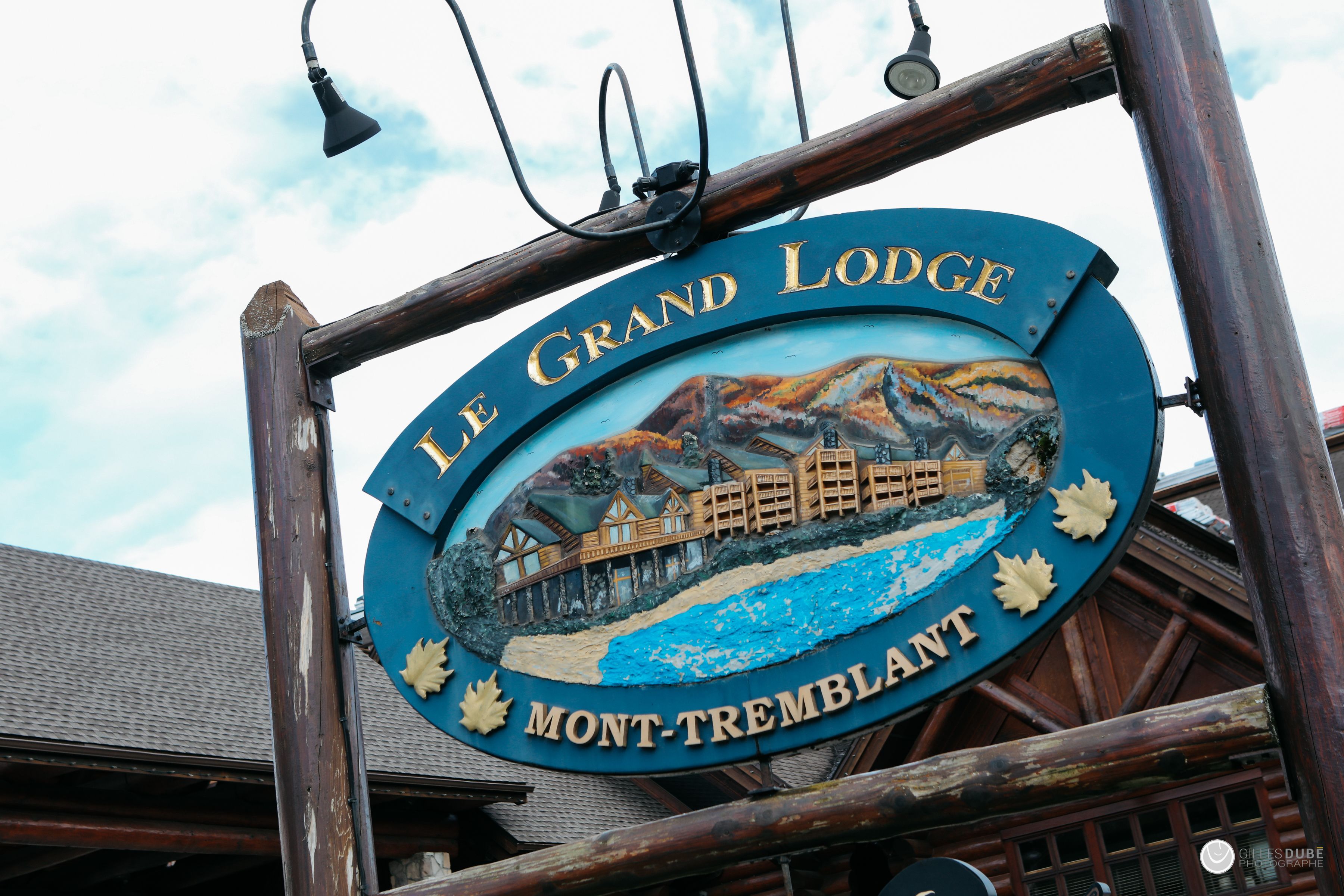 Letrero de Le Grand Lodge, con un marco de madera rústica y una pintura que muestra una montaña y un albergue.