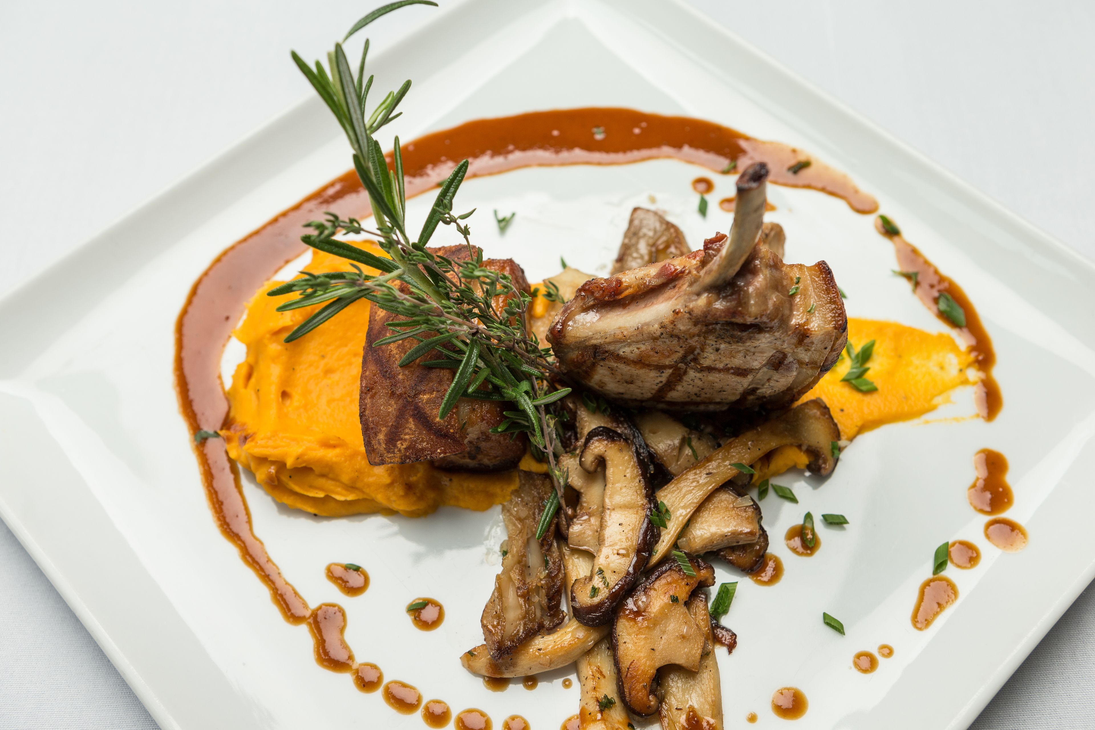 Ein Teller mit Fleisch, Pilzen und einer Dekoration.