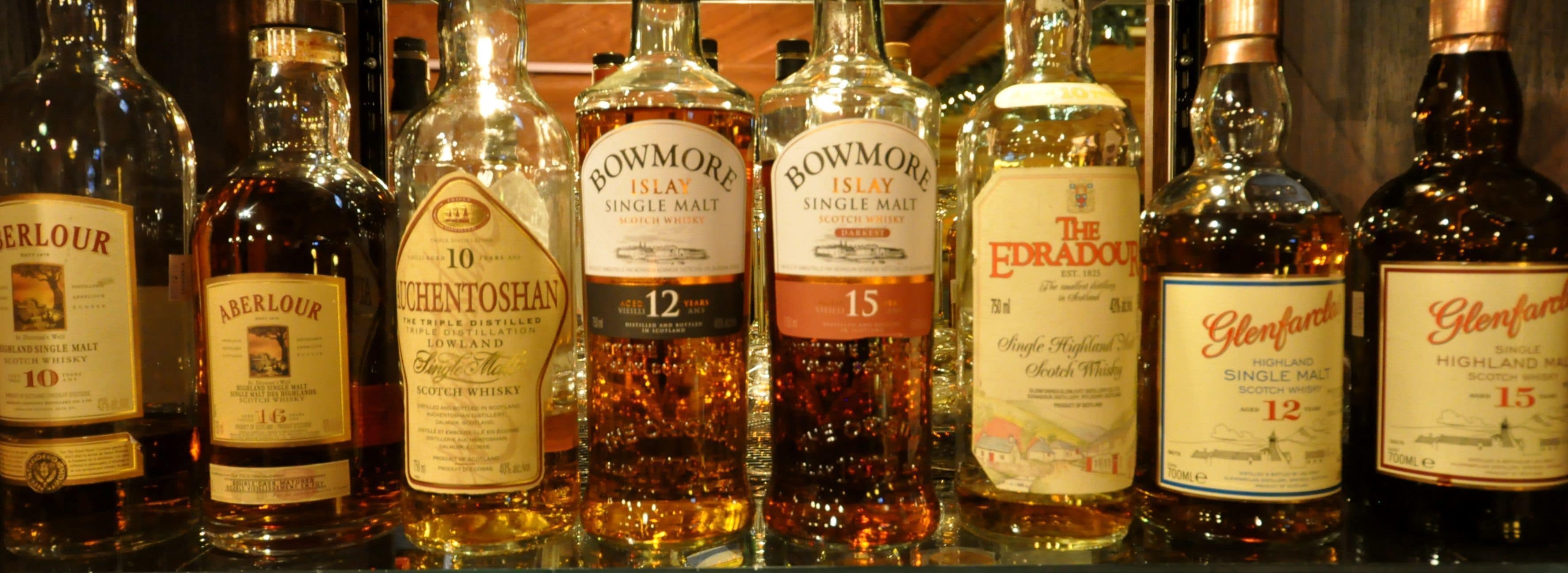 A variety of whisky bottles on a shelf.