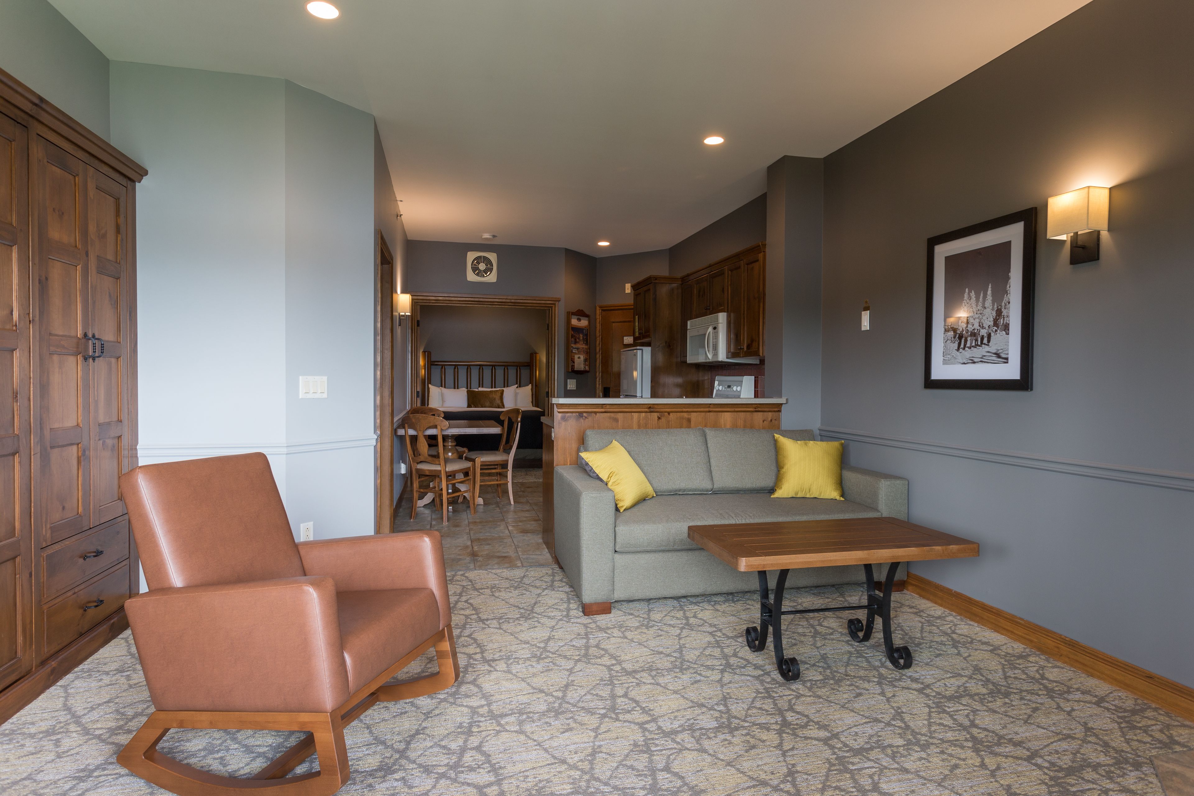A spacious living area with a sofa, a wooden coffee table, and a leather chair.