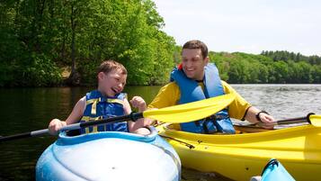 Two people in a yellow kayak on a calm river surrounded by lush greenery.