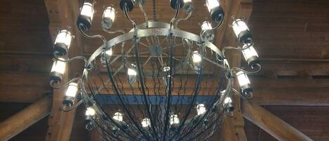 A chandelier with multiple bulbs hanging from a metal frame with a central decorative element.