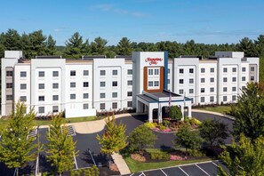 A Hampton Inn hotel with a central entrance, parking lot, and surrounding greenery. - Hampton Inn Boston Bedford Burlington (Billerica)