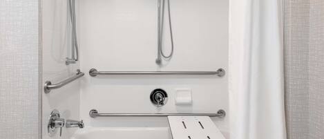 A modern bathroom with a bathtub, a shower with a handheld showerhead, and grab bars for safety.
