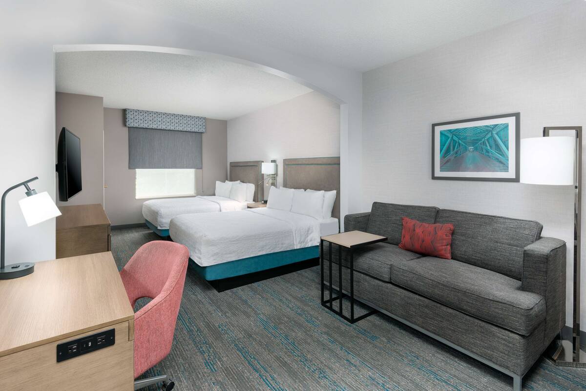 A hotel room with a bed, a sofa, a desk, and a TV.