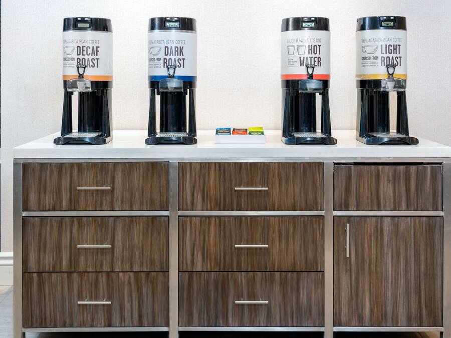 A coffee station with four dispensers labeled Decaf Roast, Dark Roast, Hot Water, and Light Roast.