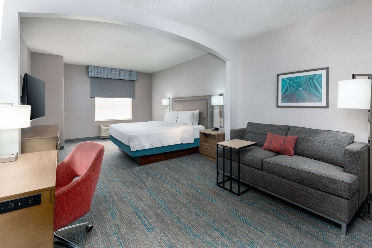 A hotel room with a bed, a sofa, a desk, and a TV.
