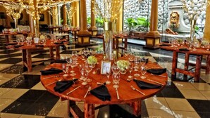 A restaurant with round tables set for dining, featuring a checkered floor pattern and warm lighting. - Hotel Villa Caletas (Tárcoles)
