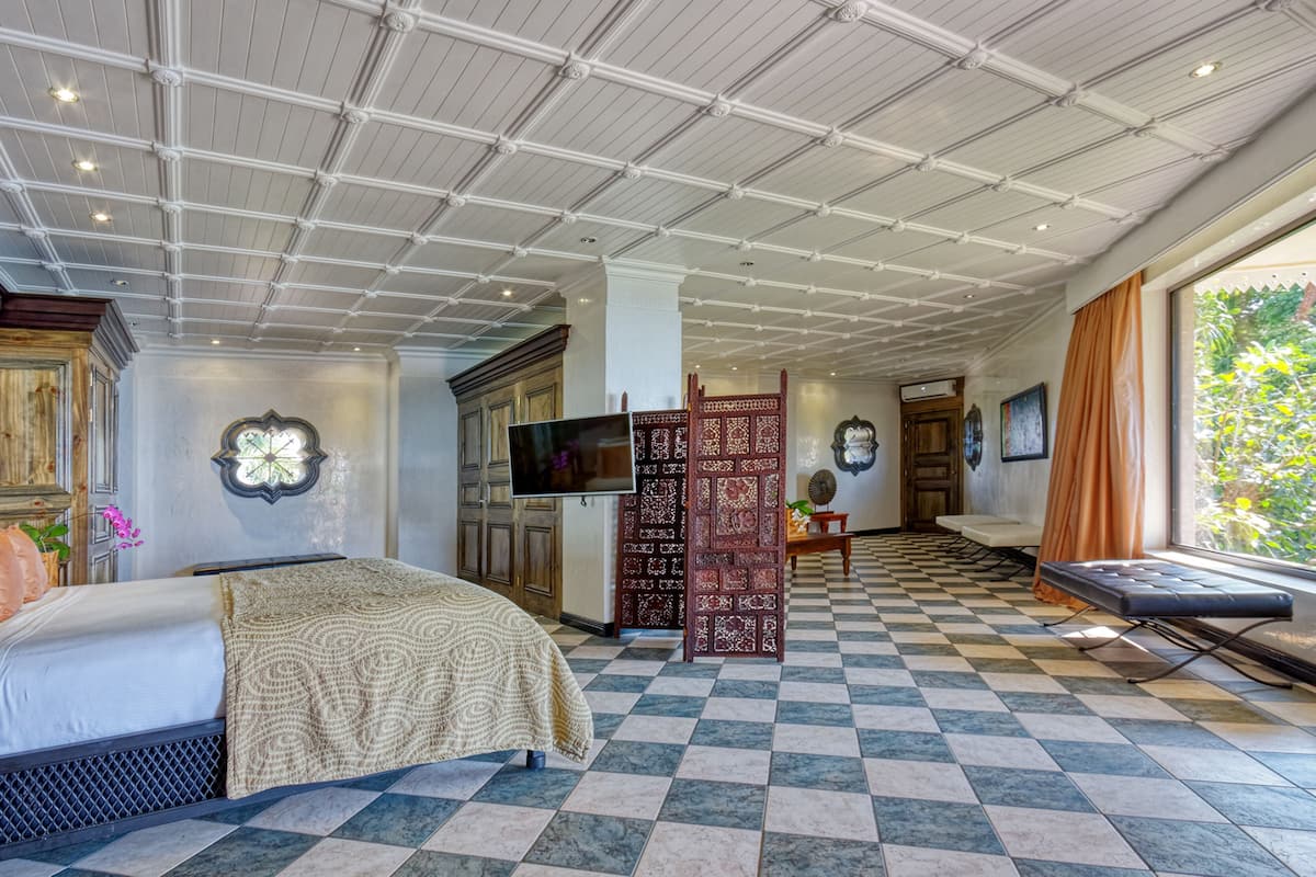 A spacious room with a large bed, a television, and a decorative screen.