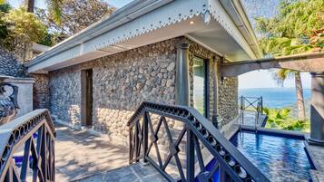 A stone building with a pool, a staircase, and a view of the ocean.