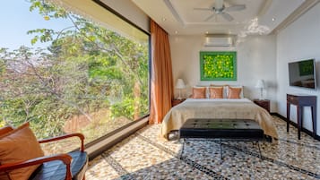 A modern bedroom with a large window, a bed, a TV, and a ceiling fan.