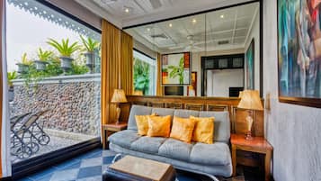A modern living room with a grey sofa, orange cushions, a wooden coffee table, and two side tables with lamps.