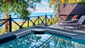 A pool area with a view of the ocean, surrounded by lush greenery and a wooden fence. - Hotel Villa Caletas (Tárcoles)